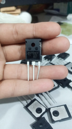 650V 75A RN75H65 RBN75H65T1 IGBT Insulated-gate Bipolar Transistor - a black three-pin electronic component held in a hand with multiple identical units scattered on a white surface in the background.
