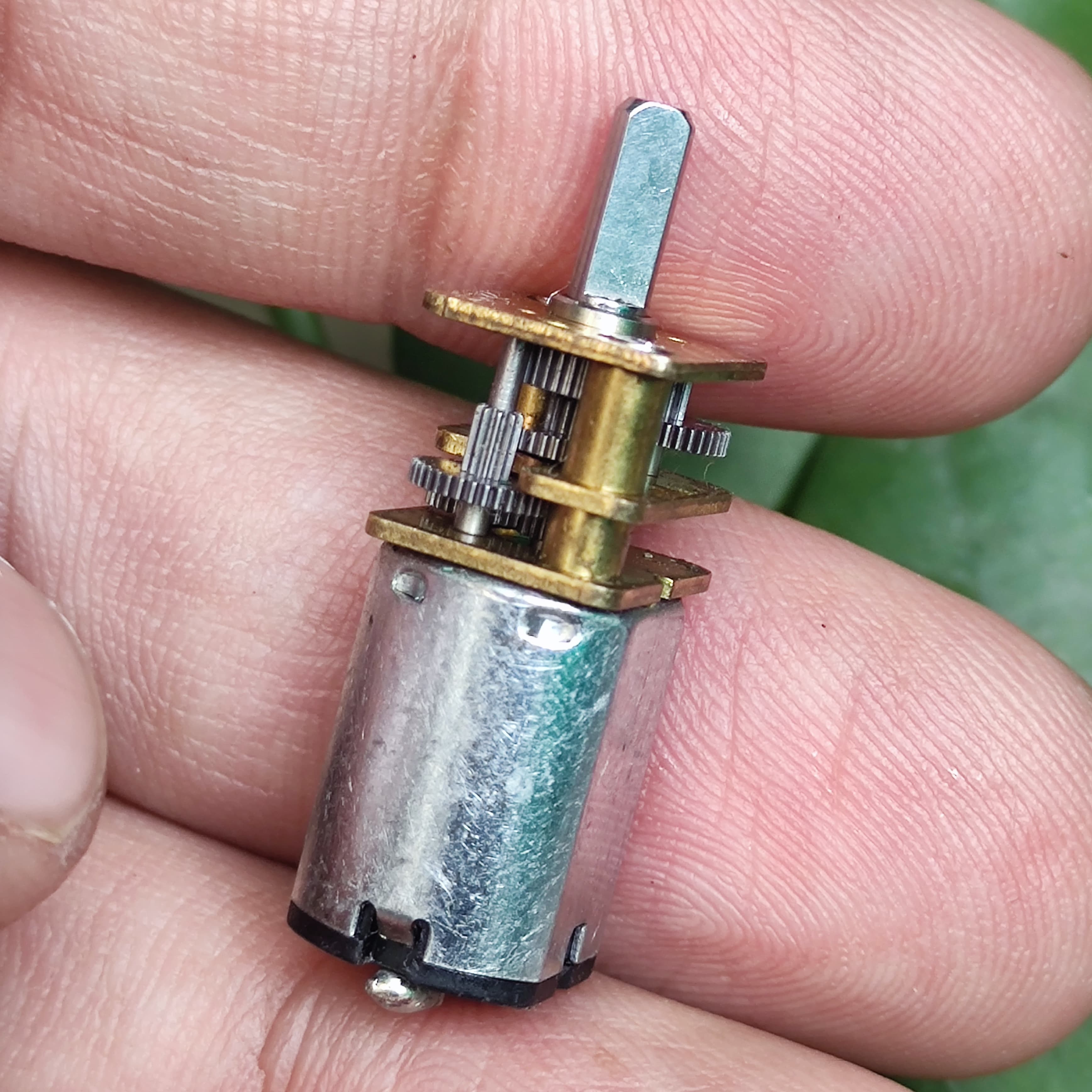68RPM N20 DC Gear Motor - shown as a close-up of the silver cylindrical motor body with an attached brass gearbox and a metal output shaft held in a hand.