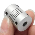 6x6mm Flexible Coupling Shaft - a silver-colored cylindrical metal component with spiral cuts and four visible black set screws, held between fingers.