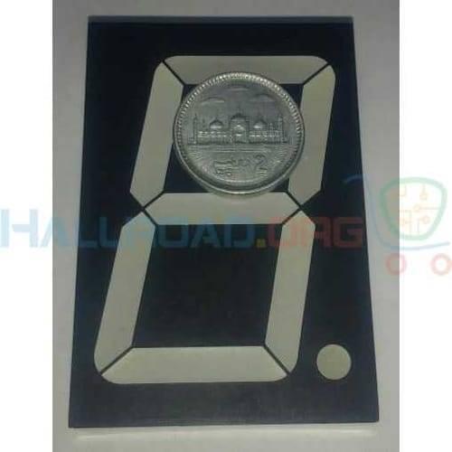 70mm Common Anode 7 Segment LED Display - a black rectangular component with white segments and a Pakistani 2-rupee coin placed on top for scale.