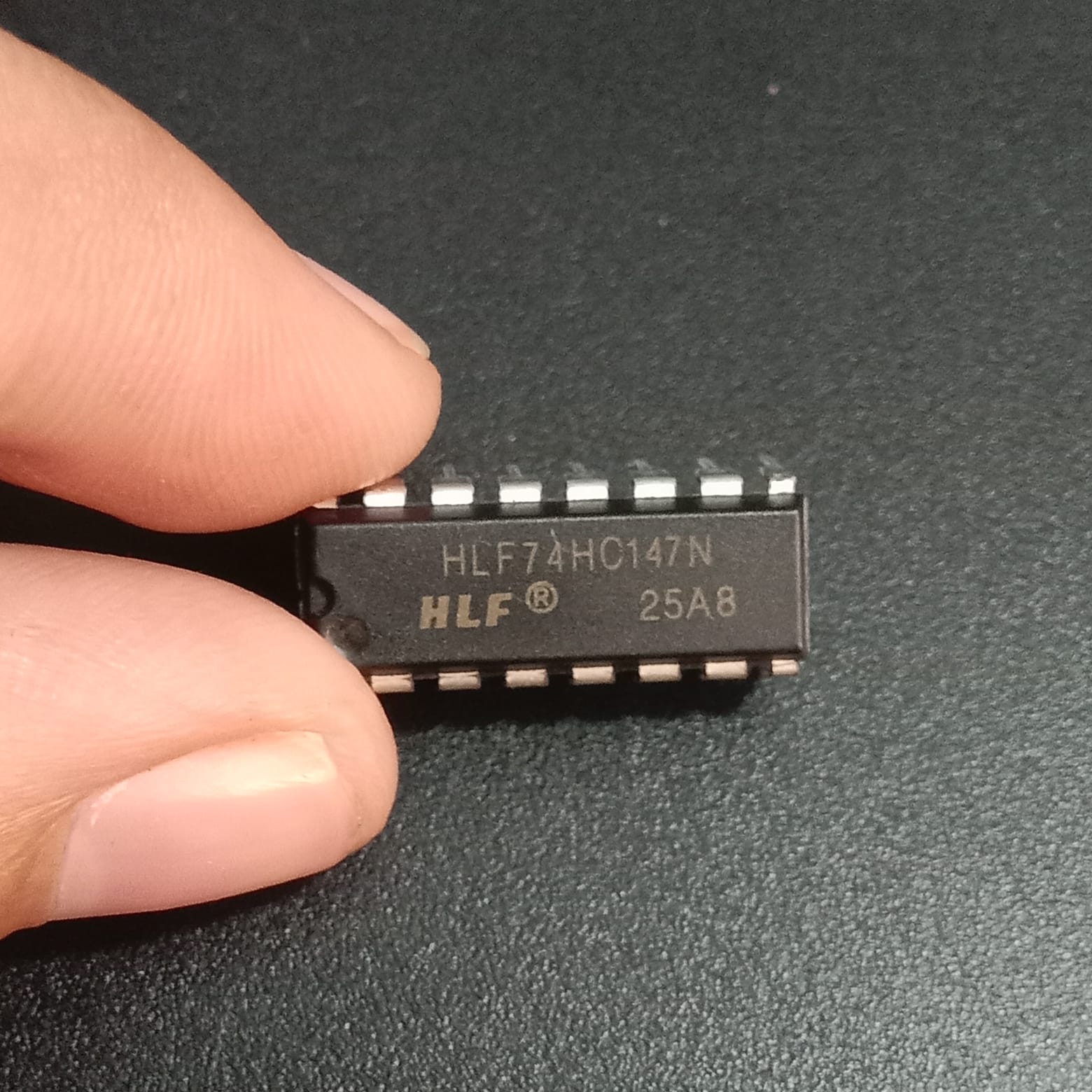 74147 HLF74HC147N 10-to-4 Line Priority Encoder IC - a black rectangular integrated circuit held by fingers, showing the printed model number.