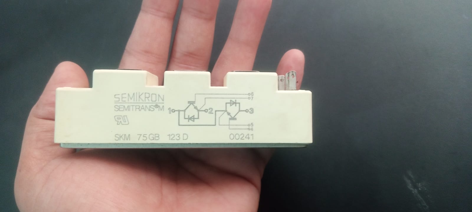 75A 1200V IGBT Module - a rectangular beige electronic component held in a hand, showing a printed circuit diagram and terminal pins on its side.