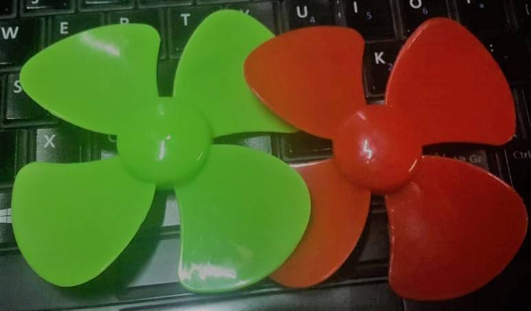 75mm 4 Vane Propeller For Small Motor - one green and one orange four-blade plastic propeller resting on a computer keyboard.
