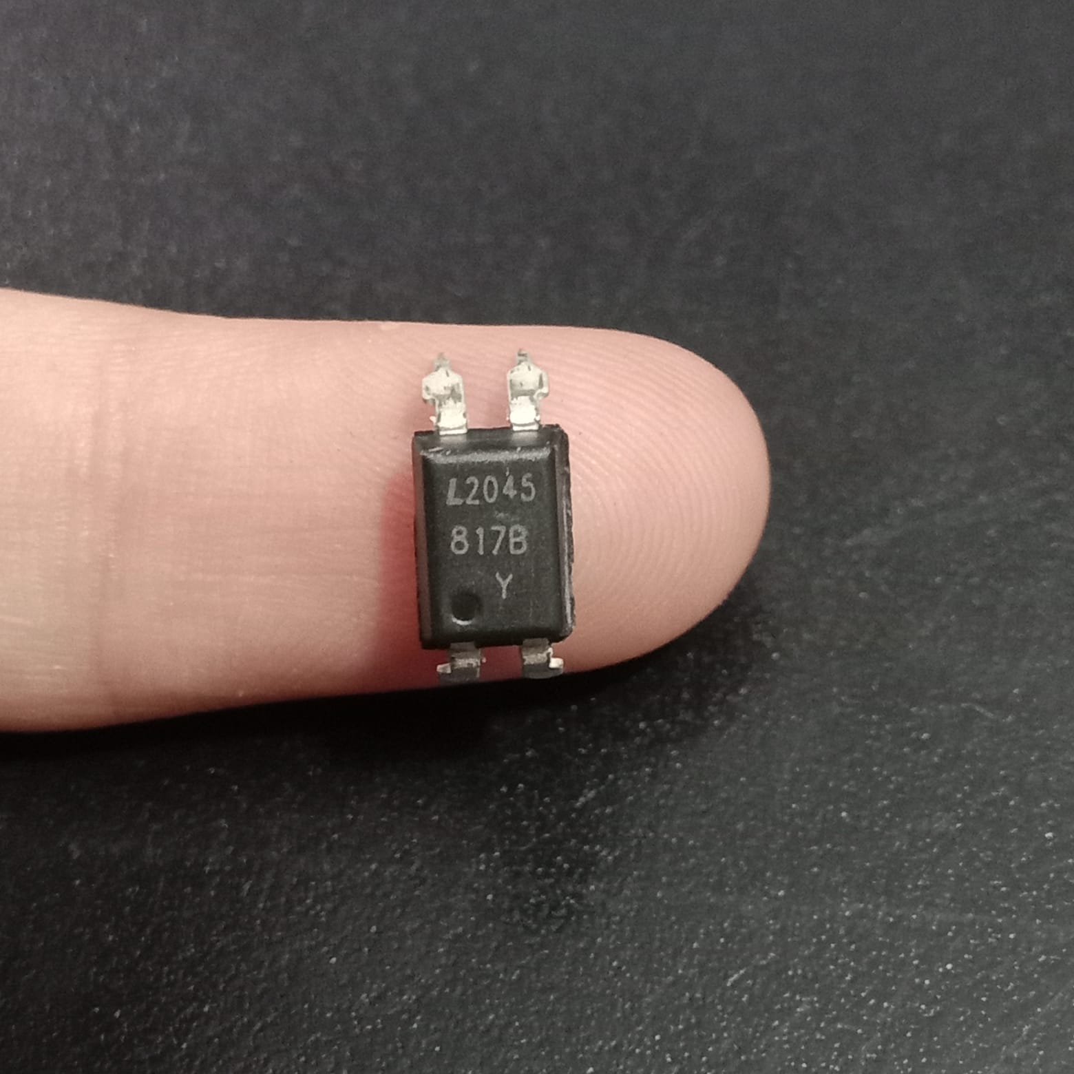 817B Optocoupler - a black, rectangular four-pin electronic component held between fingers, showing the text L2045, 817B, and Y printed on its surface.