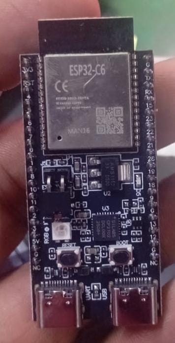 ESP32-C6 microcontroller development board held in a person's hand, showing the black PCB with the ESP32-C6 chip, connectors, and small electronic components.