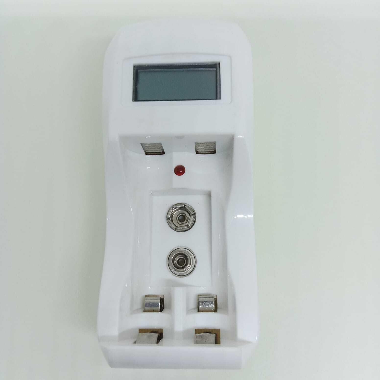 AA Ad AAA Cell And Battery Charger 1.2V And 9V - a white plastic charging unit featuring a blank LCD screen, a red indicator light, and battery slots.