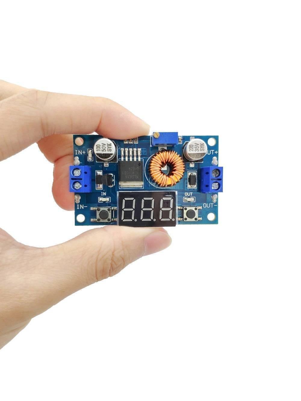Adjustable Step Down Power Supply Module With Voltmeter Display XL4015 - held in a hand, featuring a blue circuit board, a digital display, and terminals.