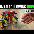 Arduino Human Following Robot (Unassembled Only Parts) - four-wheeled robotic chassis with a red T-shaped sensor mount and yellow wheels on a wooden surface.