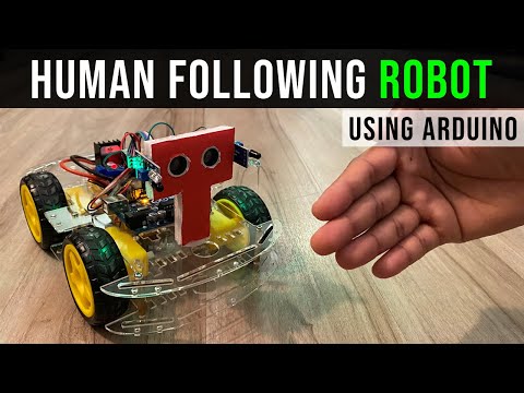 Arduino Human Following Robot (Unassembled Only Parts) - four-wheeled robotic chassis with a red T-shaped sensor mount and yellow wheels on a wooden surface.