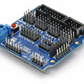 Arduino Sensor Shield V5 Expansion Board For Arduino - a blue rectangular circuit board with numerous pin headers, a reset button, and a blue terminal block.