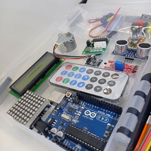 Arduino Starter Kit - an Arduino Uno board, LCD screen, remote control, stepper motor, ultrasonic sensor, and various electronic components in a box.