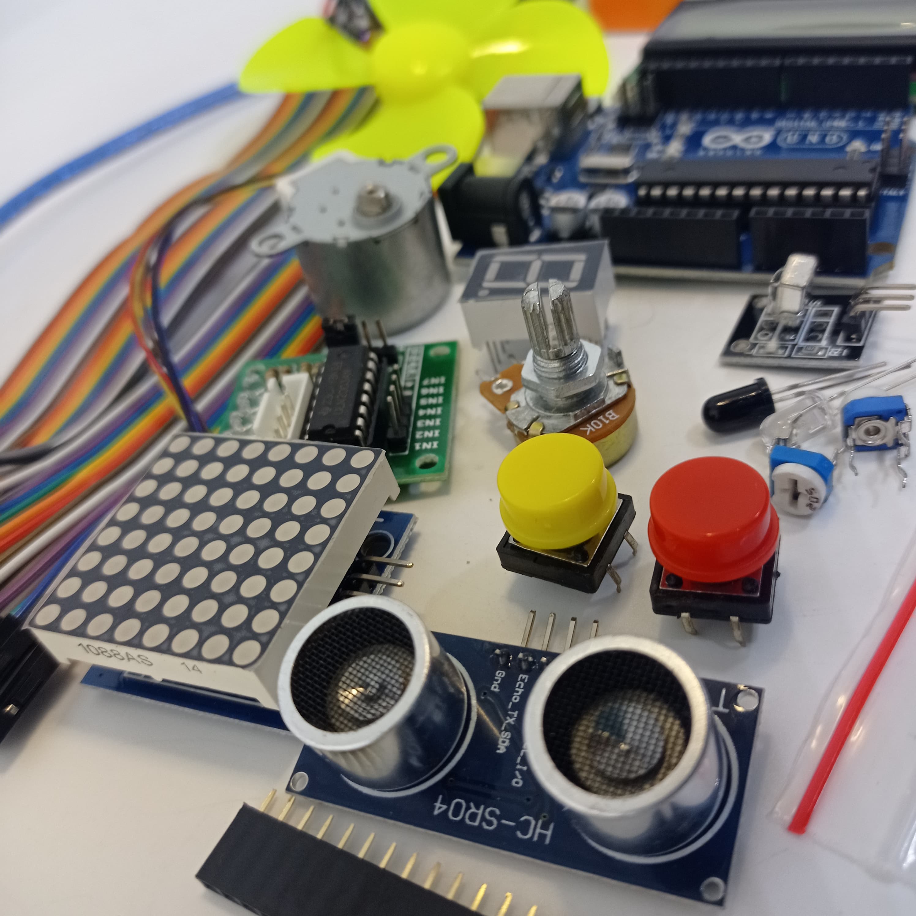 Arduino Starter Kit - an assortment of electronics including an Arduino board, ultrasonic sensor, LED matrix, motor, buttons, and jumper wires.