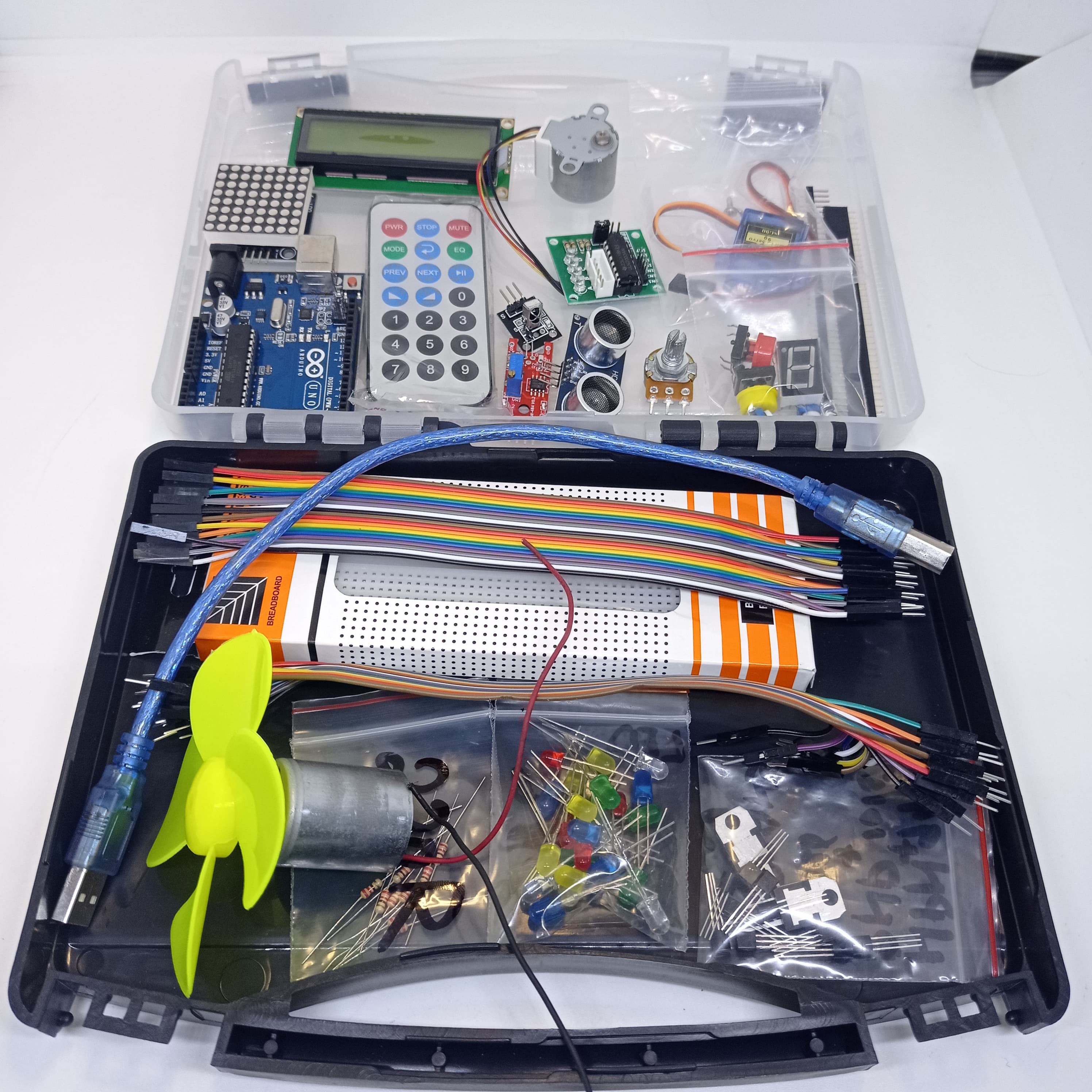 Arduino Starter Kit - shown in an open black plastic case containing an Arduino Uno board, LCD screen, remote, breadboard, jumper wires, motor, and LEDs.