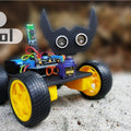 Arduino Voice Controlled kit - assembled as a four-wheeled robot with yellow wheels, a black bat-shaped ultrasonic sensor head, and a Bluetooth module.