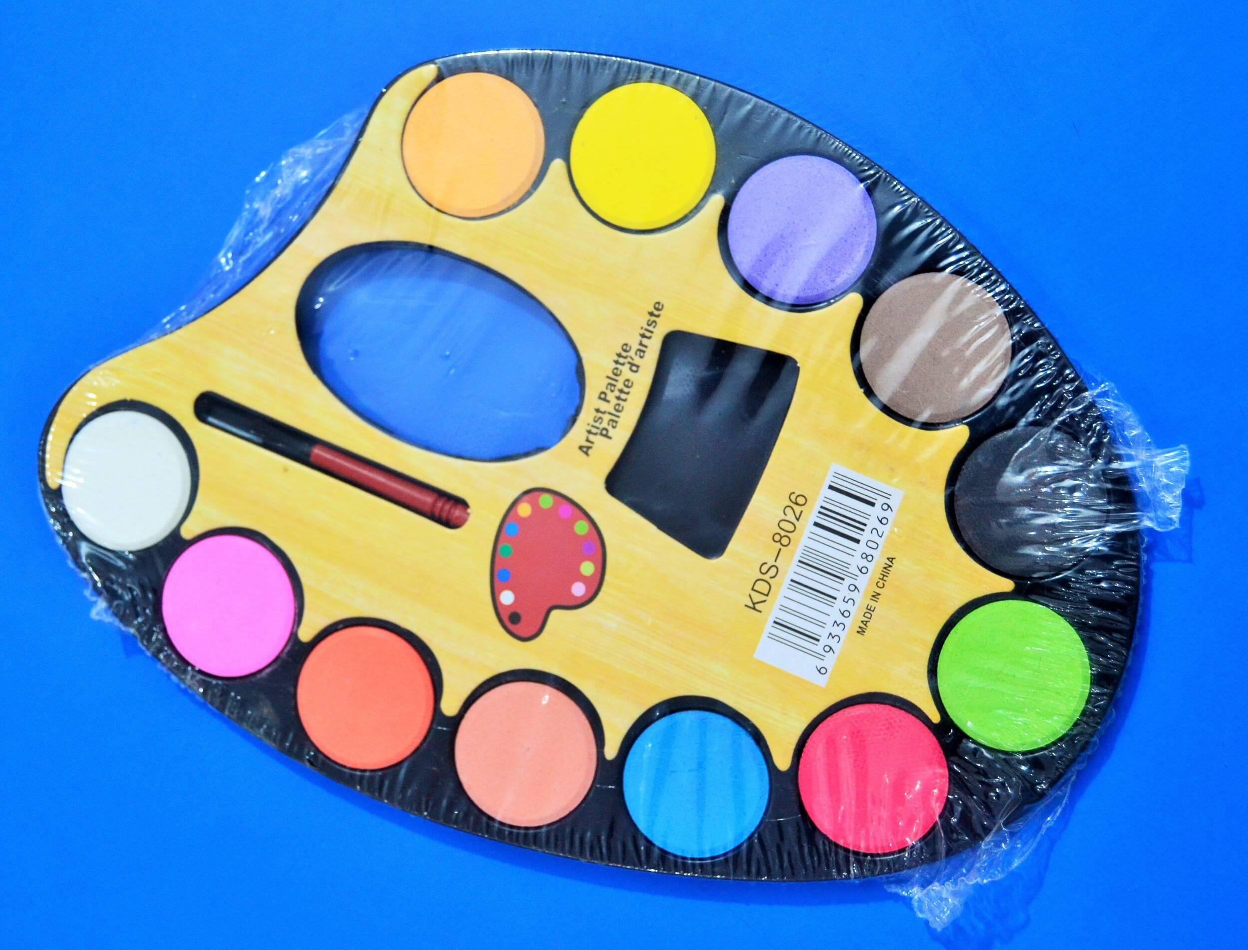 Artist Palette 12 Water Color Paints For Kids - Large Water Colors 12 Color - Brush - containing twelve circular paint cakes and a brush, sealed in clear plastic packaging.