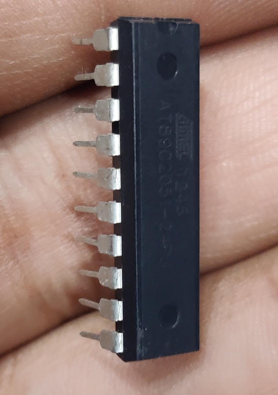 AT89C2051-24PU AT89C2051 AT89C4051 Microcontroller IC Atmel DIP-20 - a black 20-pin DIP integrated circuit held in a hand, showing the Atmel logo and model text on its top surface.