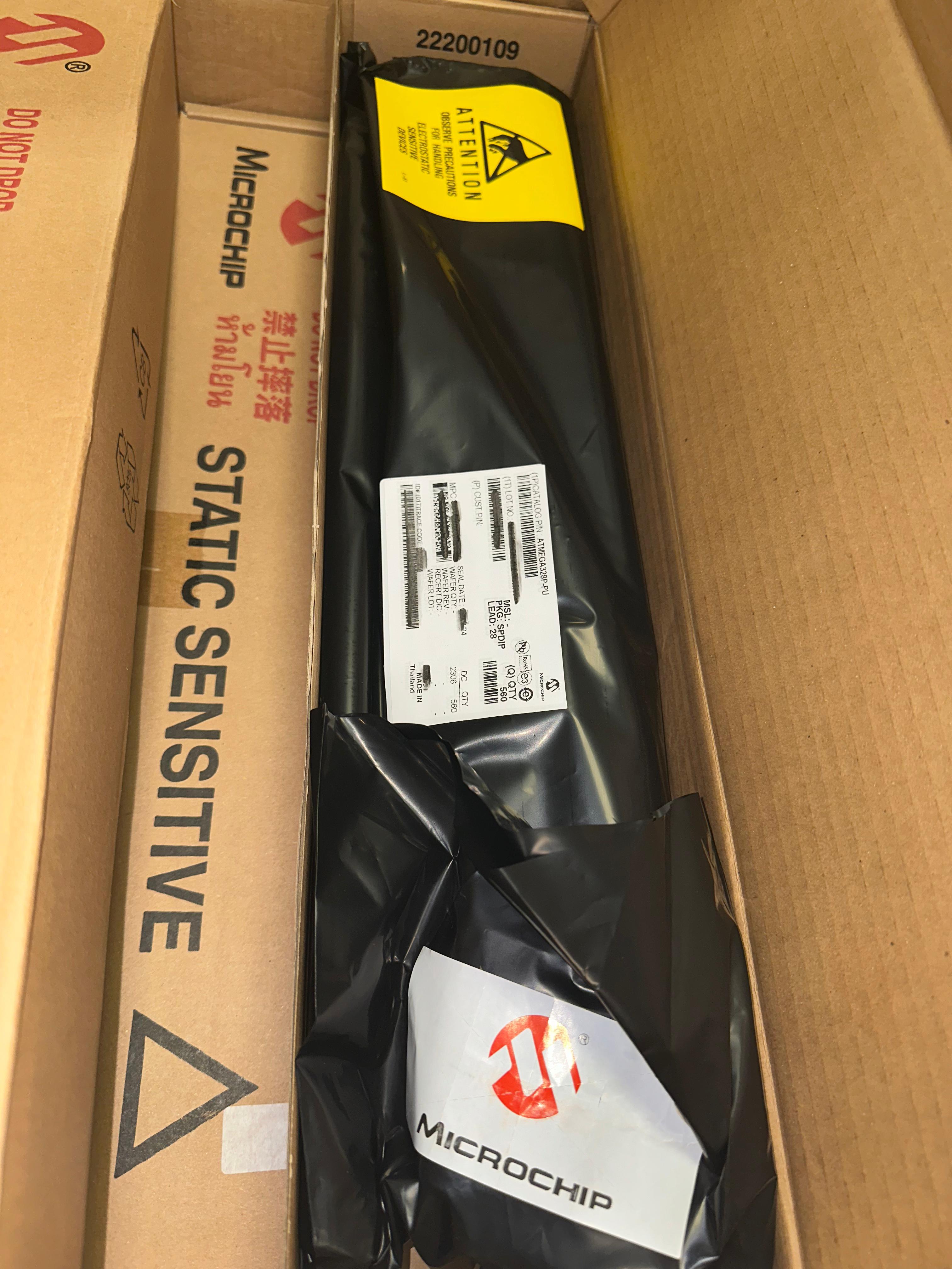 ATMEGA328P-U Microcontroller | High-performance MCU | Digilog.pk - shown in a factory-sealed black anti-static tube inside a cardboard shipping box with Microchip branding and product labels.