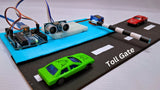 Automatic Car Parking Toll Gate System - an Arduino board, ultrasonic sensor, and servo-controlled barrier arm with two toy cars on a road model.