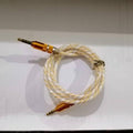 Aux Cable - a coiled white and yellow braided wire with gold-coloured 3.5mm connectors at both ends.