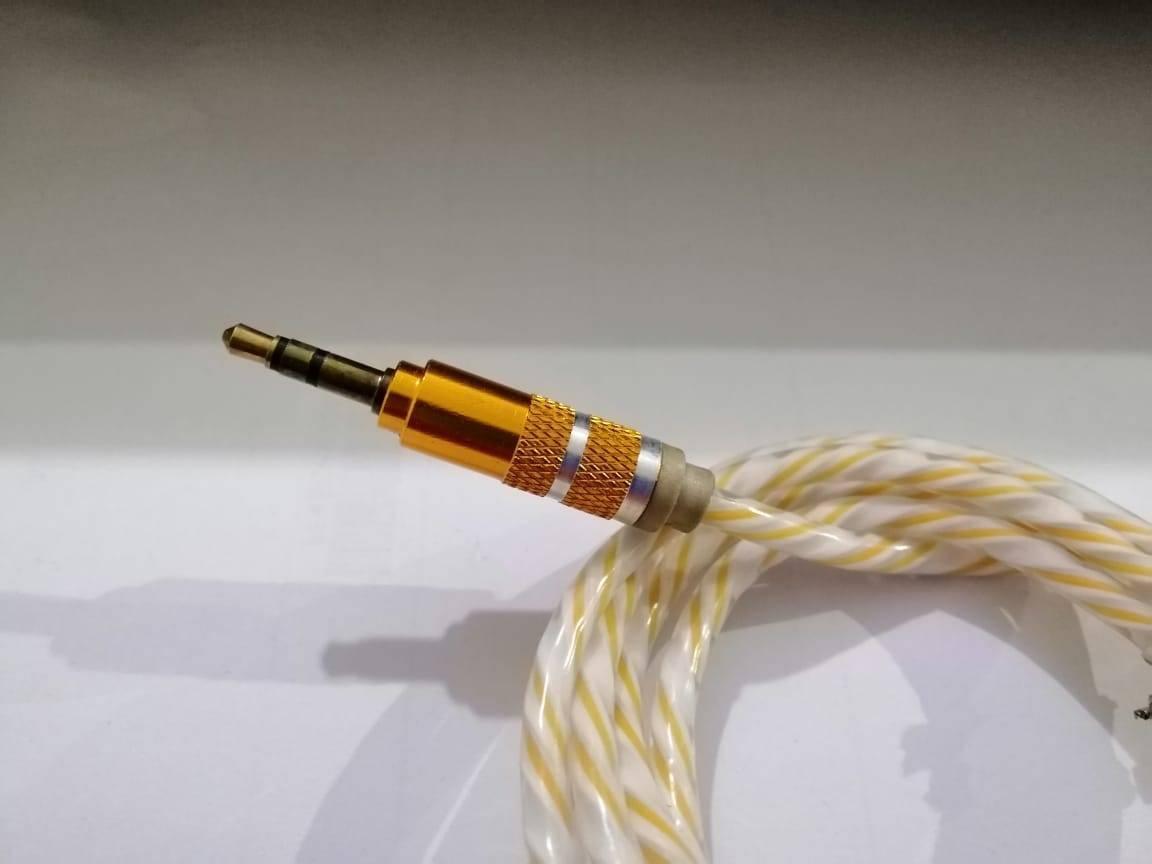 Aux Cable - a close-up of a 3.5mm gold-plated connector with a textured metallic body attached to a braided white and yellow cable.