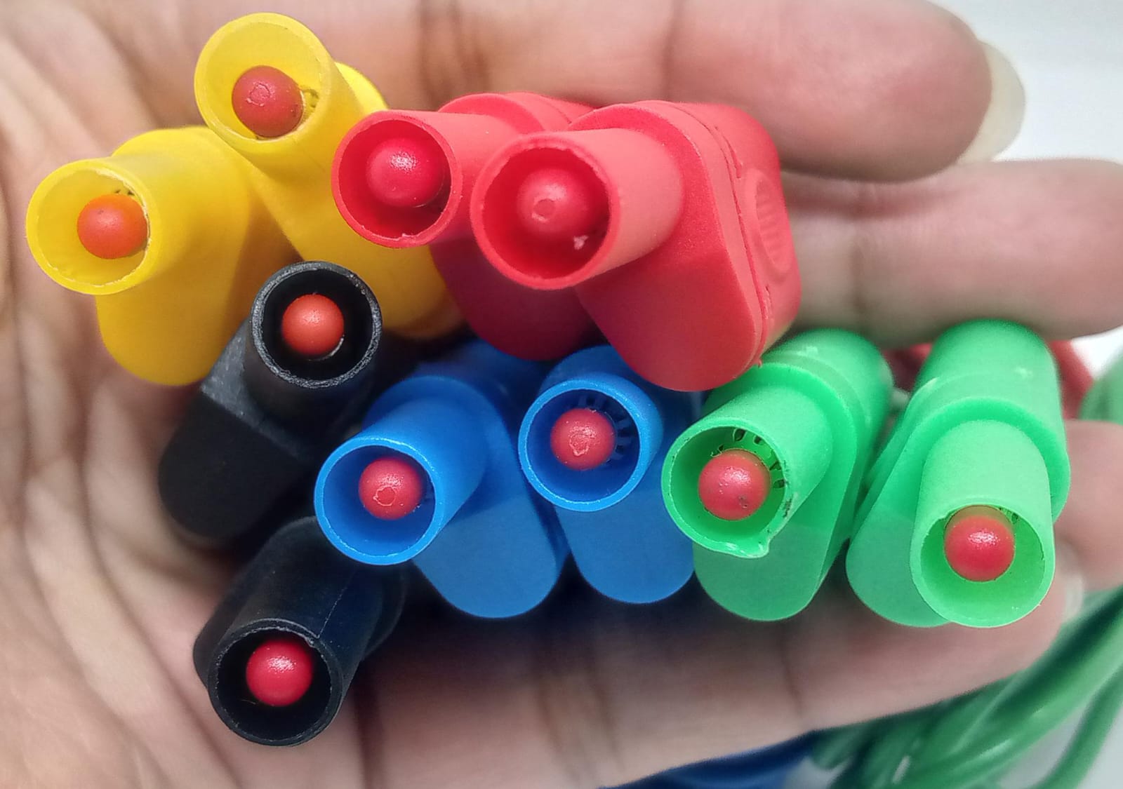 Banana Clip Wires 4mm | High-Quality Test Leads | Digilog.pk - a close-up of a hand holding a bundle of multi-coloured red, yellow, black, blue, and green 4mm banana plug connectors.