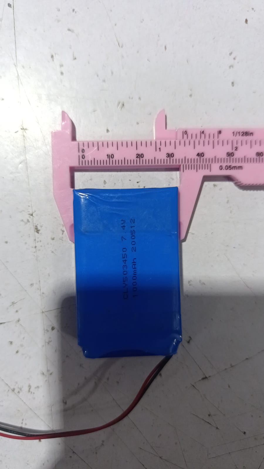 Battery Wholesale 2s 7.4V 1000mAh Rechargeable LiPo Lithium Battery Pack With JST 2.54mm Connector - shown being measured for width with a pink plastic vernier caliper on a white surface.