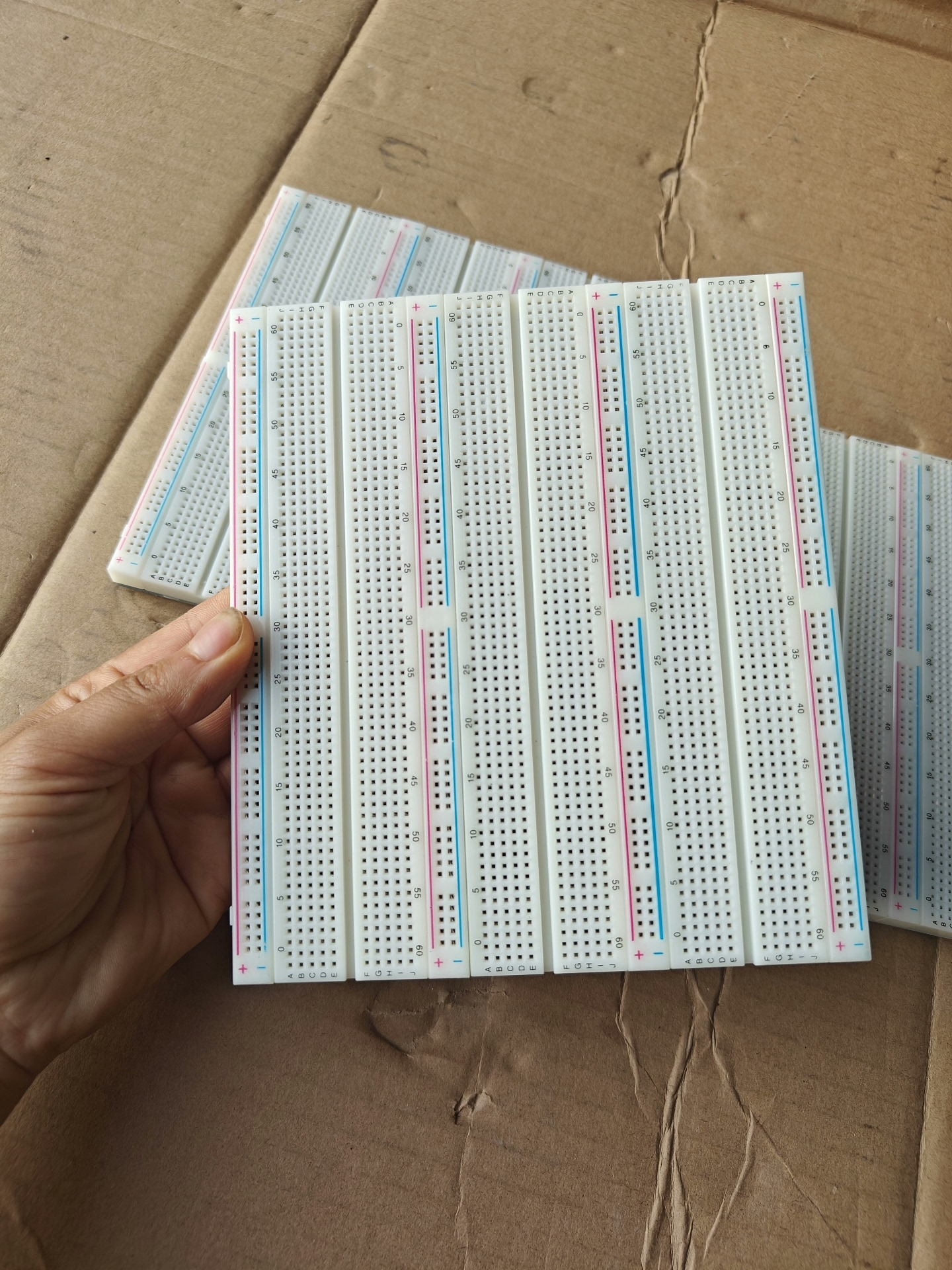 Big bread board - a large white rectangular prototyping board with multiple columns of numbered holes and red and blue power rails, held in a hand.