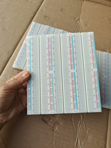 Big bread board - a large white rectangular prototyping board with multiple columns of numbered holes and red and blue power rails, held in a hand.