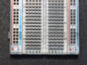 Breadboard MB102 830 Point Clear -transparent - a close-up view showing the numbered rows 50 to 60 and lettered columns a-e and f-j on the clear surface.