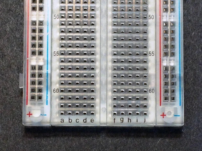 Breadboard MB102 830 Point Clear -transparent - a close-up view showing the numbered rows 50 to 60 and lettered columns a-e and f-j on the clear surface.