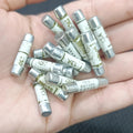 BS1362 13A Ceramic Fuse - shown as a pile of multiple white cylindrical ceramic fuses with metal end caps held in a person's hand.