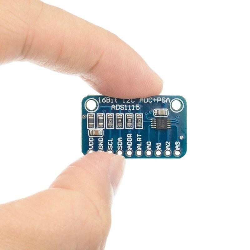 Buy ADS1115 16 Bit ADC 4 Channel With Programmable Gain Amplifier - held by fingers, showing the blue rectangular circuit board with labeled pins and chip.