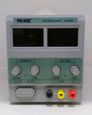 Buy Ps 303A Volder 30V 3A Variable DC Power Supply – Digilog.pk - a grey rectangular device with two blank digital displays, four adjustment knobs, a power button, and three output ports.