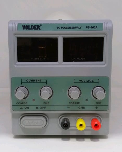 Buy Ps 303A Volder 30V 3A Variable DC Power Supply – Digilog.pk - a grey rectangular device with two blank digital displays, four adjustment knobs, a power button, and three output ports.