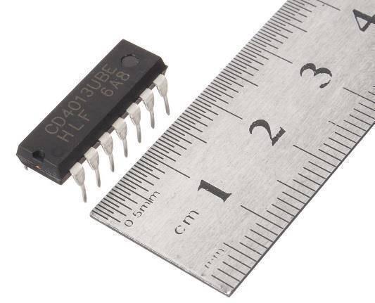 CD4013 d Type Flip Flop - shown as a black 14-pin integrated circuit chip positioned next to a metal ruler for scale.