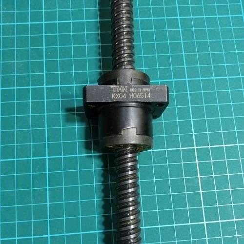 CNC Ball Screw - a black metal screw shaft with a THK branded nut assembly featuring the text KX04 H06514, resting on a green cutting mat.