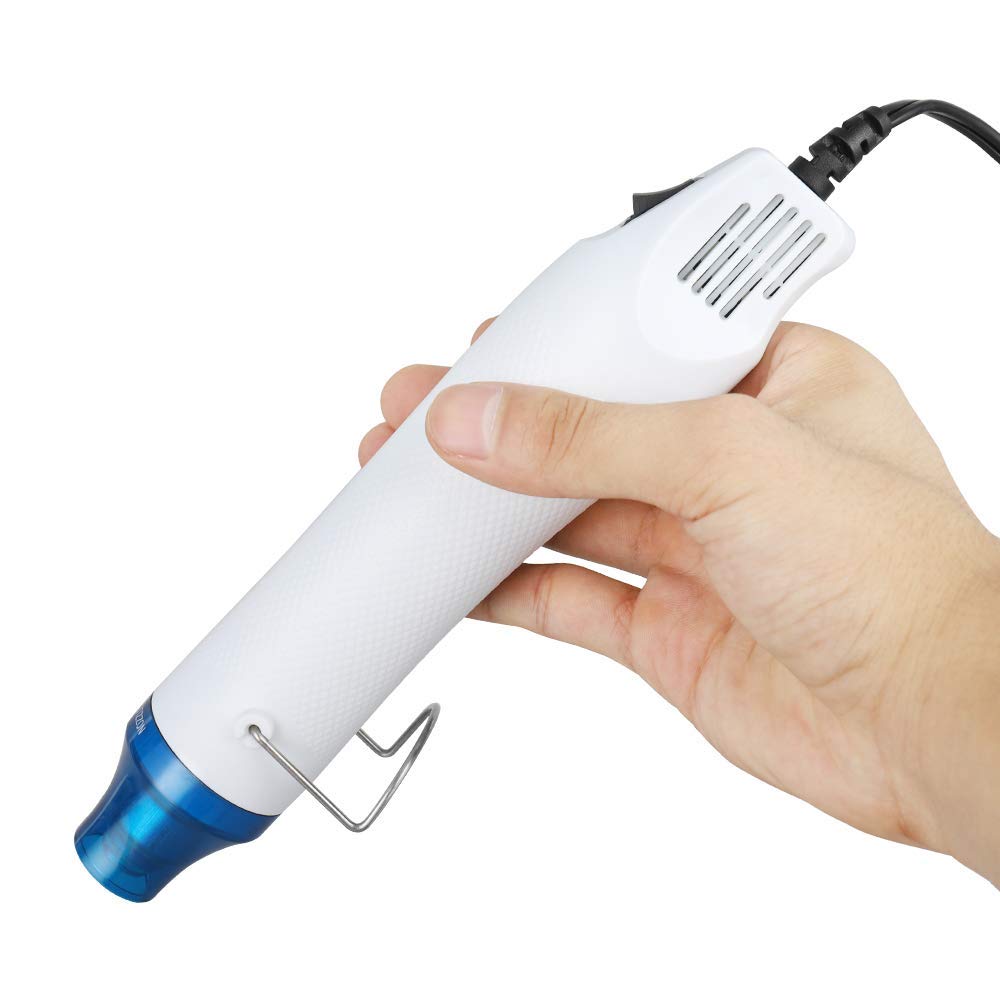 Compact 300W Mini Heat Gun – Portable Craft Heat Tool For DIY, Embossing, Paint Drying & Shrink Wrap - shown in a hand, featuring a white cylindrical body, a blue nozzle, a power cord, and a small metal stand.