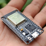 Compatible Wroom ESP32 WiFi Based Microcontroller Development Board Nodemcu CH9102X - held in a hand, showing the silver ESP-32 shield, micro-USB port, BOOT button and labelled GPIO pins on both headers.