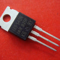 Copy IRF540 - a black, three-pin electronic transistor with a metal mounting tab, shown in a close-up against a solid red background.