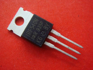 Copy IRF540 - a black, three-pin electronic transistor with a metal mounting tab, shown in a close-up against a solid red background.