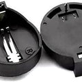 CR2032 Coin Cell Battery Holder - two black plastic circular battery holders with metal contact pins, one viewed from the top and one from beneath.