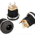 DC-022 DC Power Jack PCB Mount Female Connector 3 Pin With Nut 5.5mm x 2.1mm - three black cylindrical units with metal nuts and exposed metal pins shown from multiple angles.