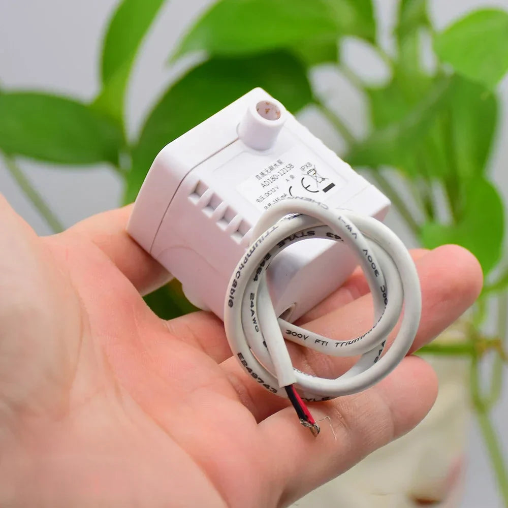 DC Brushless Water Pump DC 12V 2W Submersible Pump Fish Tank Rockery Circulation - shown as a white, compact submersible pump held in a hand with an attached white electrical cable and exposed wires.