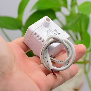 DC Brushless Water Pump DC 12V 2W Submersible Pump Fish Tank Rockery Circulation - shown as a white, compact submersible pump held in a hand with an attached white electrical cable and exposed wires.