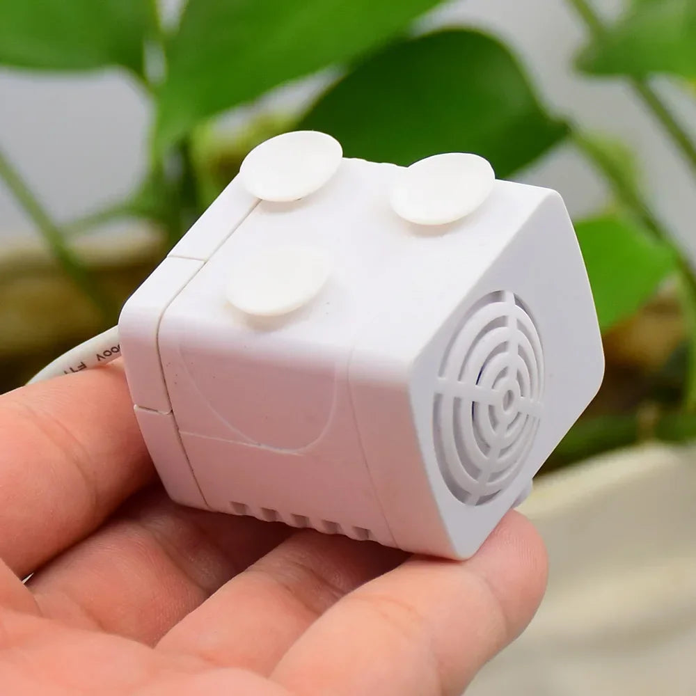 DC Brushless Water Pump DC 12V 2W Submersible Pump Fish Tank Rockery Circulation - a small white submersible pump held in a hand, featuring a circular intake grille and two suction cups on the side.