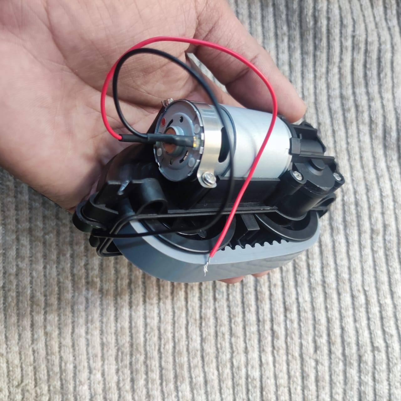 DC Gear Motor With 3.7V To 12V Operated - held in a hand, showing a silver cylindrical motor attached to a black plastic gearbox with red and black wires.