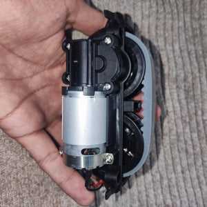 DC Gear Motor With 3.7V To 12V Operated - a silver DC motor attached to a black plastic gearbox with a white gear wheel held in a hand.