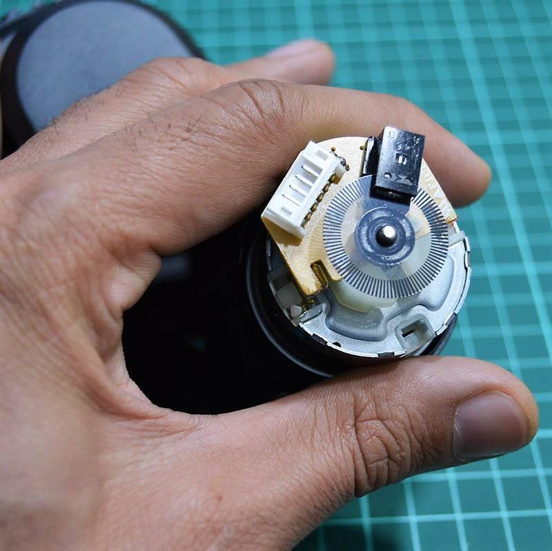 DC Gear Motor With Encoder With Wheel - close-up view of the motor rear showing the circular encoder disc, sensor module, and a white connector port.