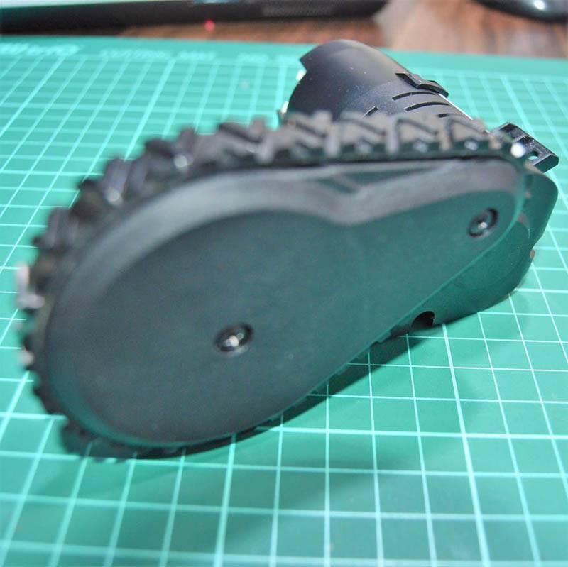 DC Gear Motor With Encoder With Wheel - a black motor assembly with a treaded rubber wheel mounted on a green cutting mat.
