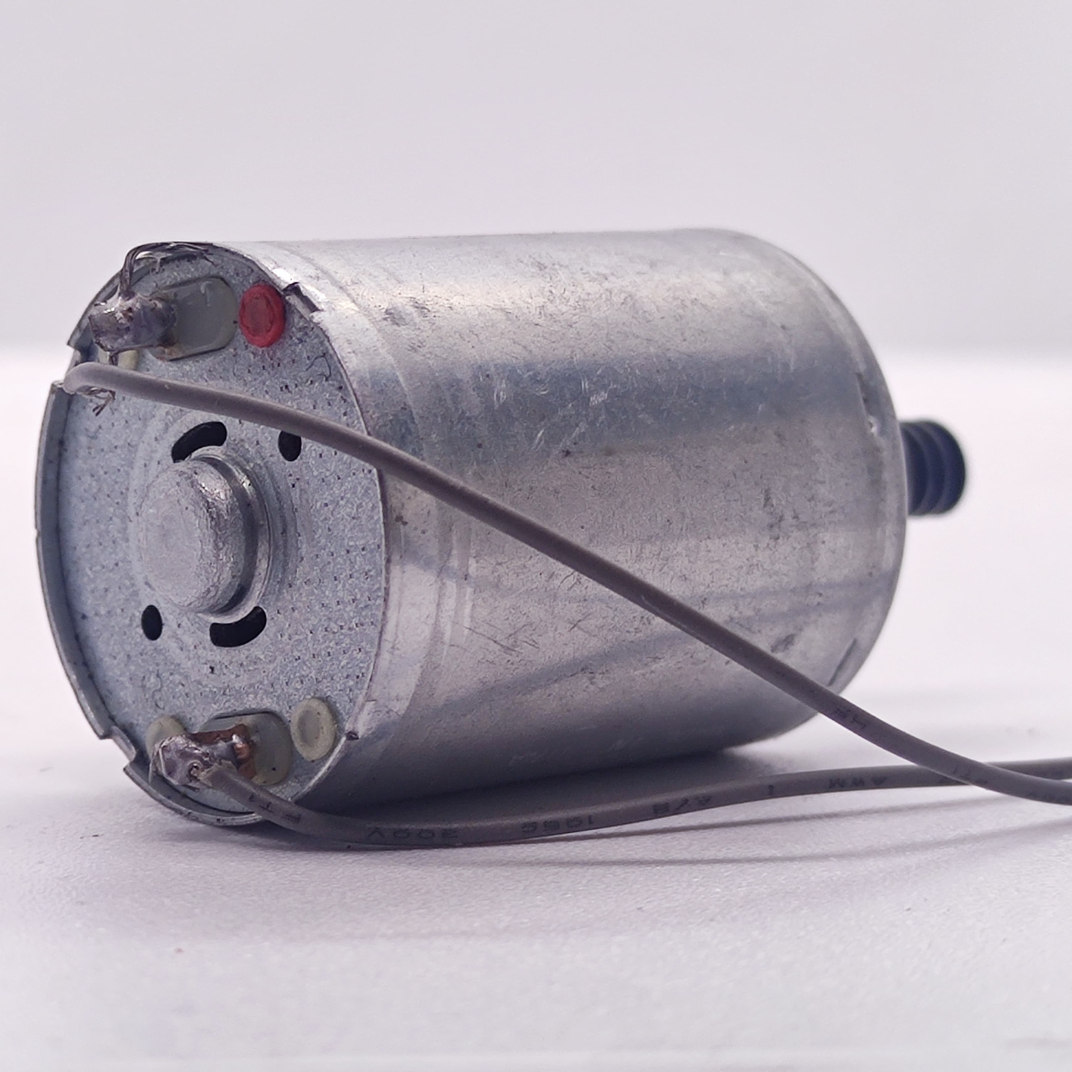 DC Motor 2V To 24V 5100RPM - a silver cylindrical motor with two electrical terminals soldered to grey wires and a small black gear on the output shaft.